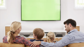 86206658-vista-posteriore-della-famiglia-seduta-sul-divano-in-sala-guardando-la-televisione