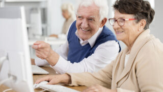 Happy senior man pointing at the computer screen